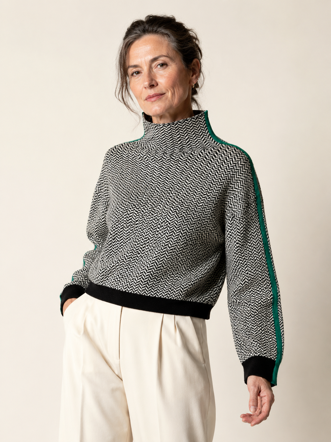 Margo & Main – Eugenie black and white chevron high collar sweater with green sleeve stripe, three-quarter view styled with cream trousers, US women's sizes