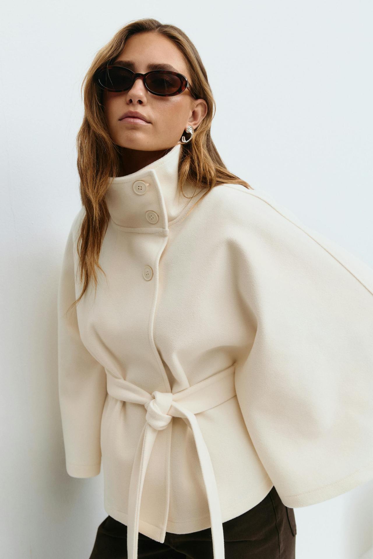 Margo & Main – Anneke ivory button-front belted cape coat, waist-up front view with the knotted belt, US women's sizes