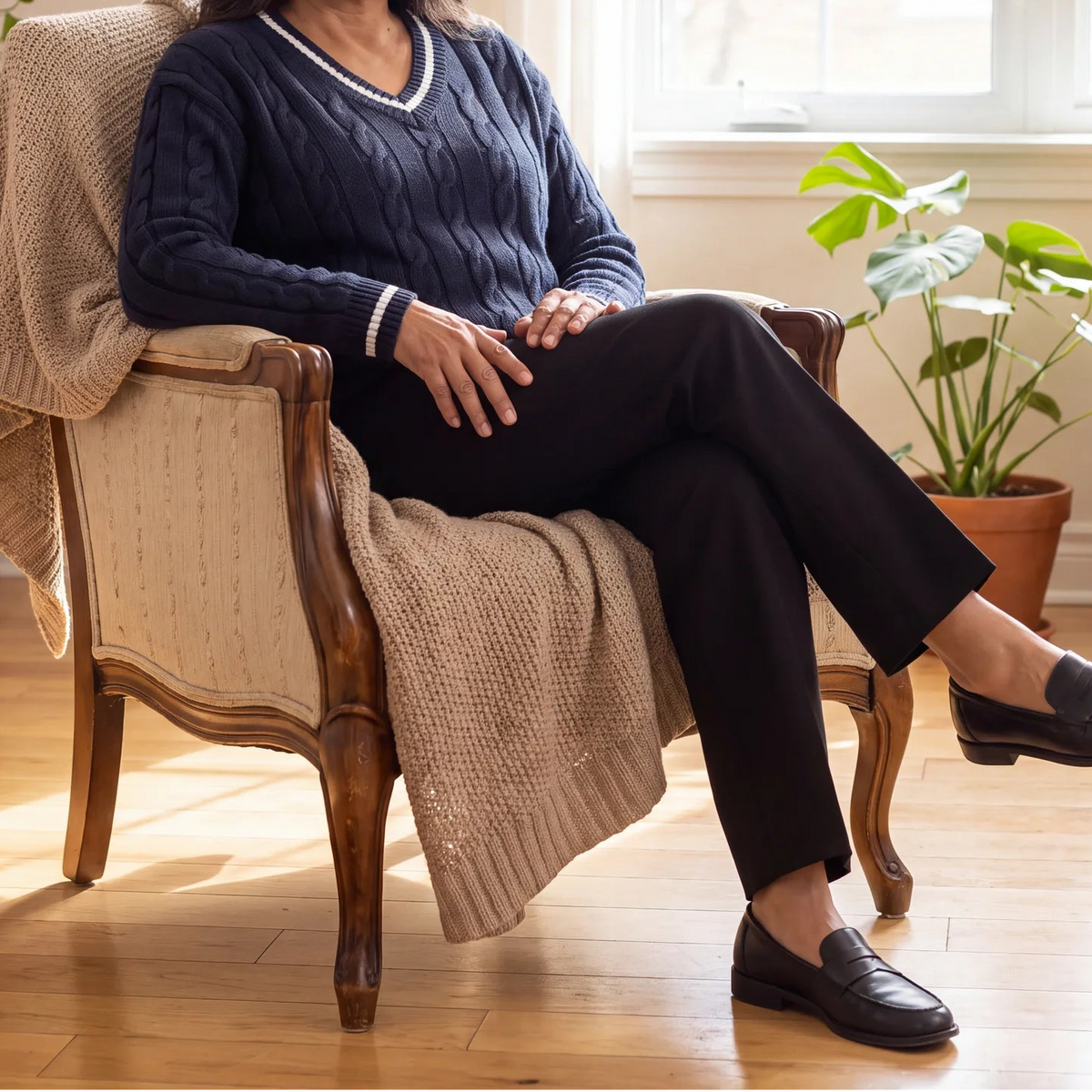Margo & Main – Blanca navy cable knit V-neck sweater, seated side view in an armchair, US women's sizes