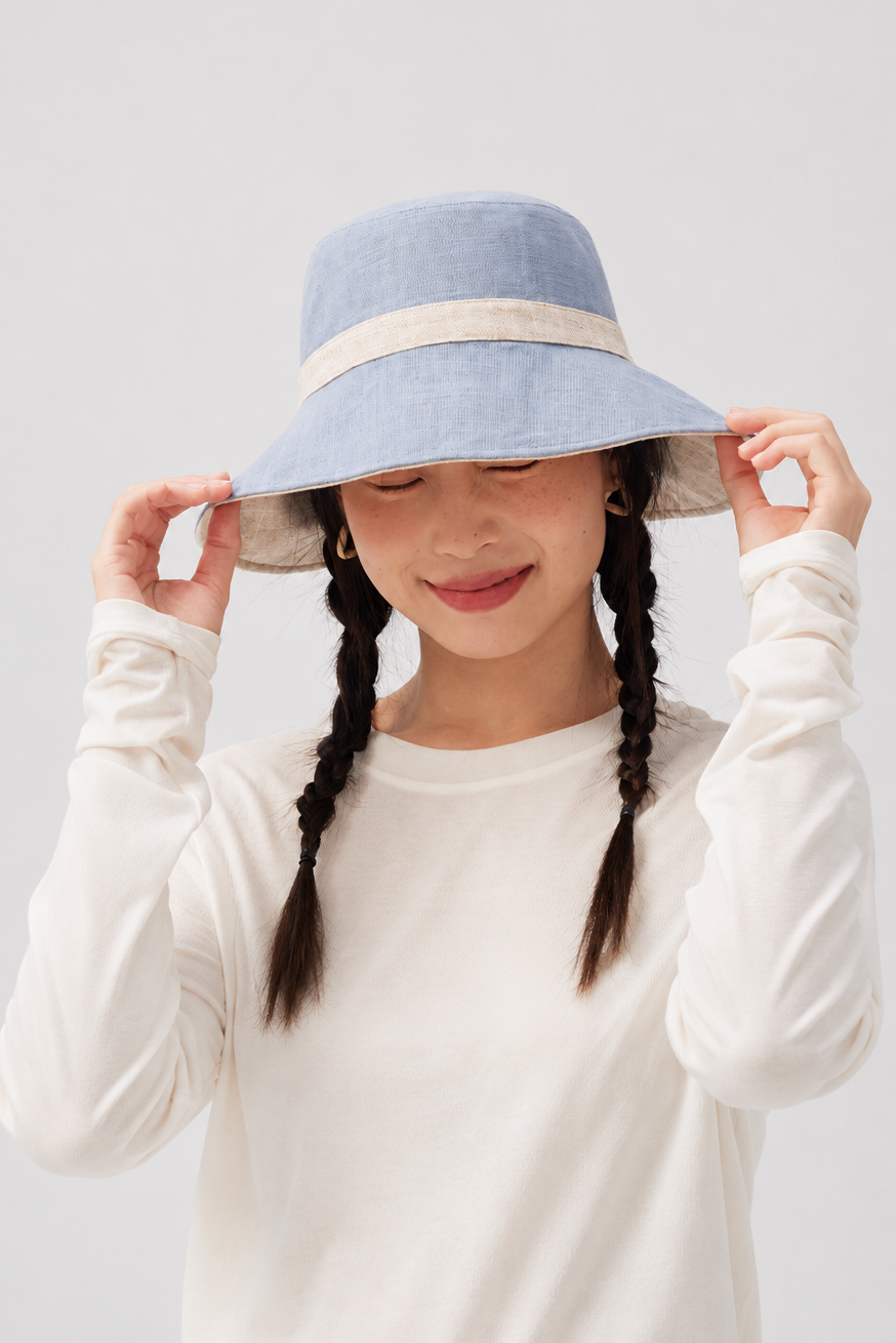 Margo & Main – Sabella light blue reversible sun hat with a natural linen band, front view with both hands on the wide brim