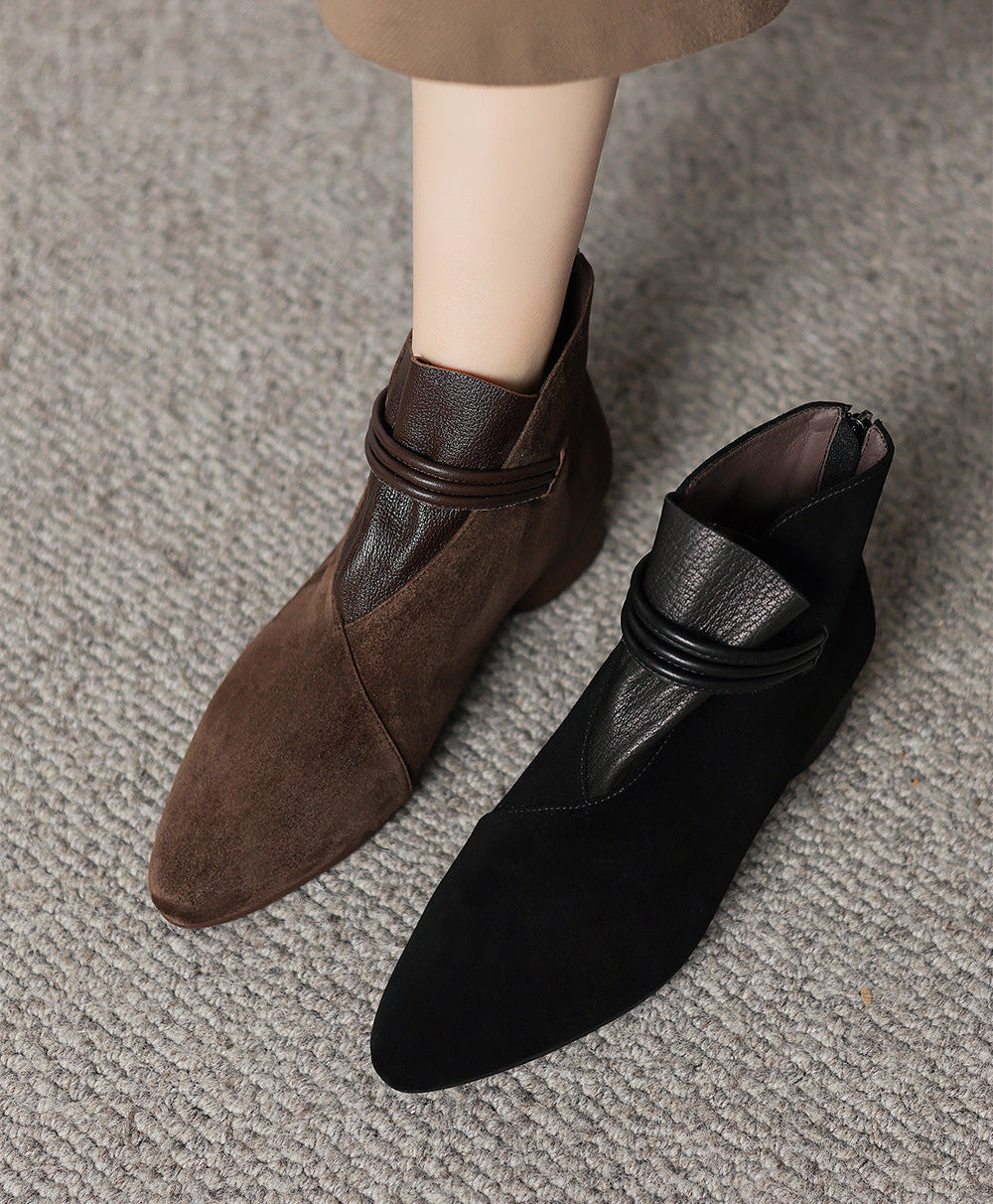 A pair of pointed-toe ankle boots shown on a mannequin leg and foot form, with one boot in brown and the other in black, placed on a gray textured carpet.