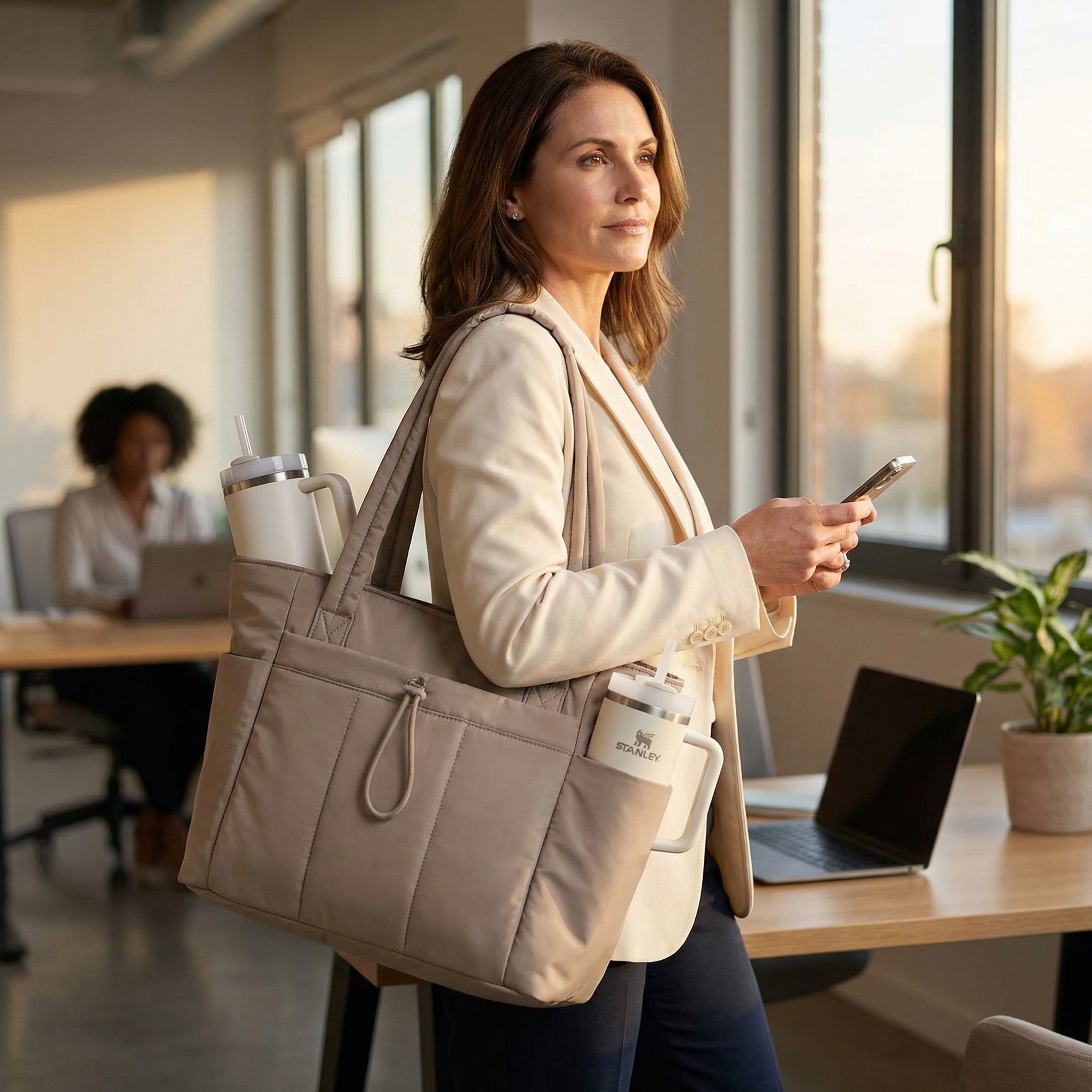 Margo & Main – Tova tan quilted work tote carried at the side while walking in an office