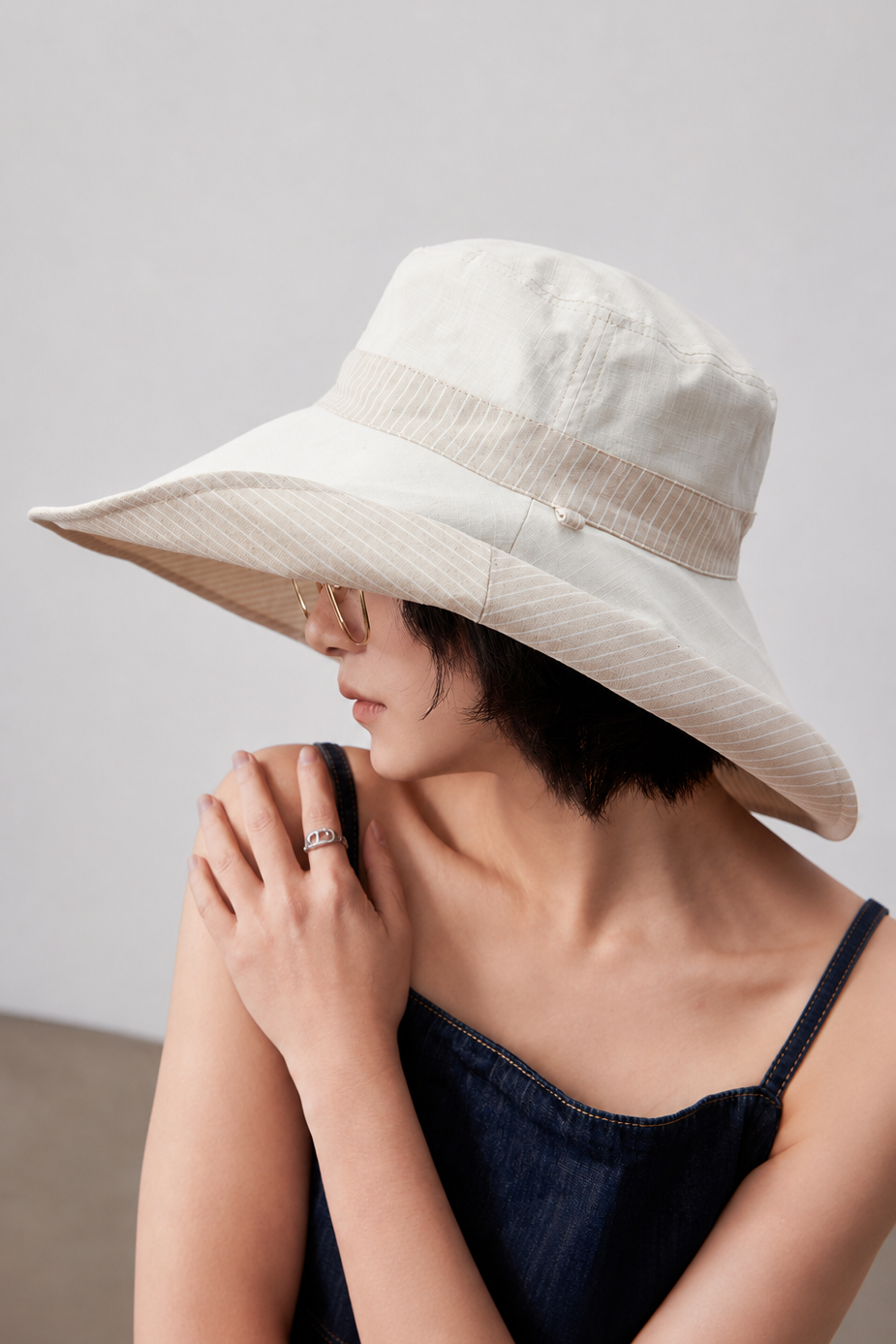Margo & Main – Carmela beige reversible wide-brim sun hat worn plain side out, three-quarter view with the striped underbrim showing