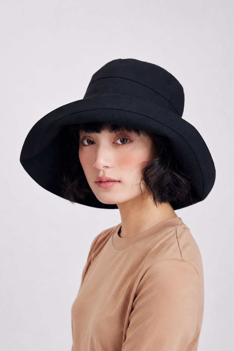 Margo & Main – Elke black wide-brim bucket sun hat, three-quarter front view on model in a tan tee