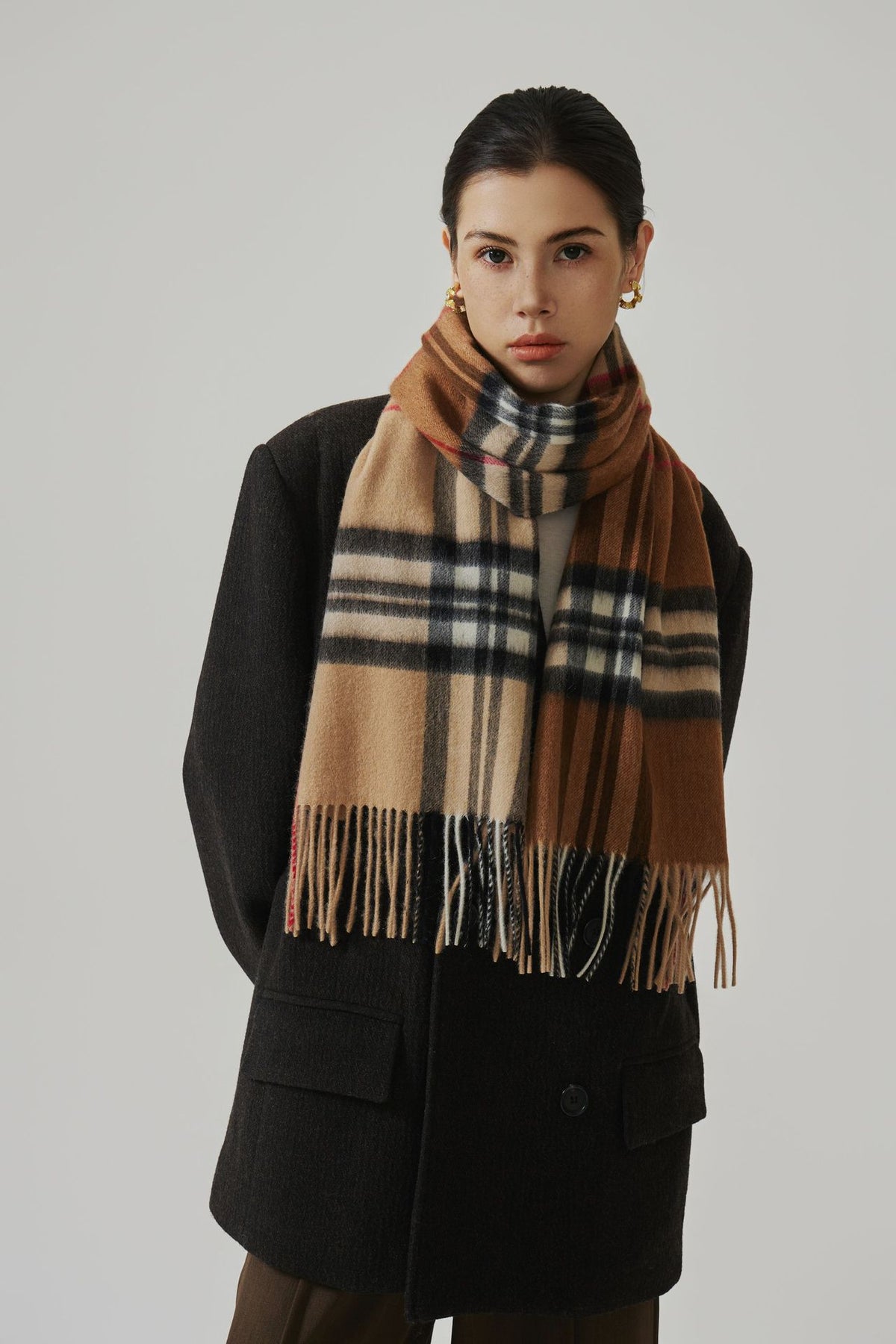 Margo & Main camel plaid lamb wool scarf — front view over a black coat with fringed ends