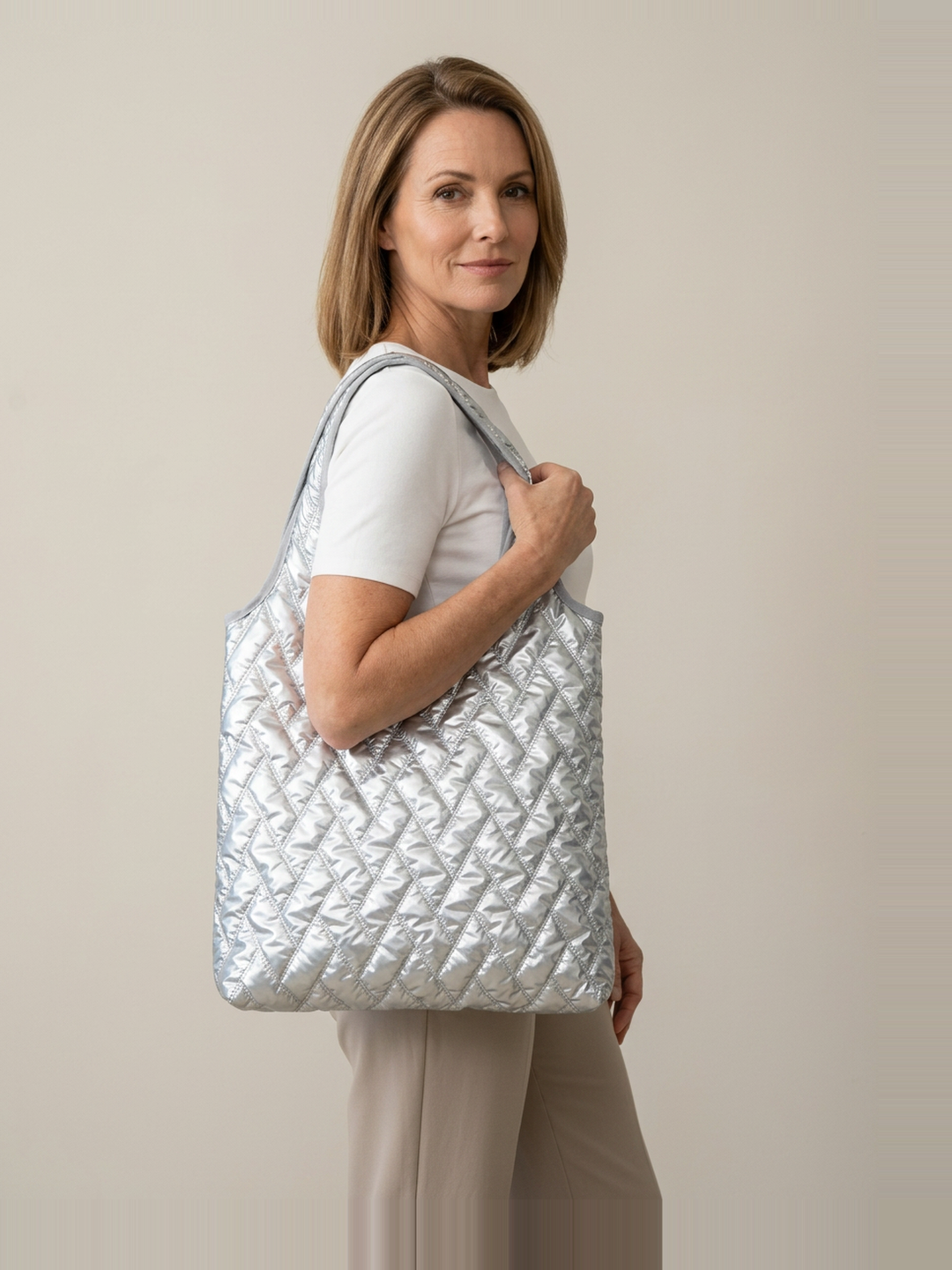 Mila Puffer Tote Bag in Silver carried by a confident woman in a clean studio setting.