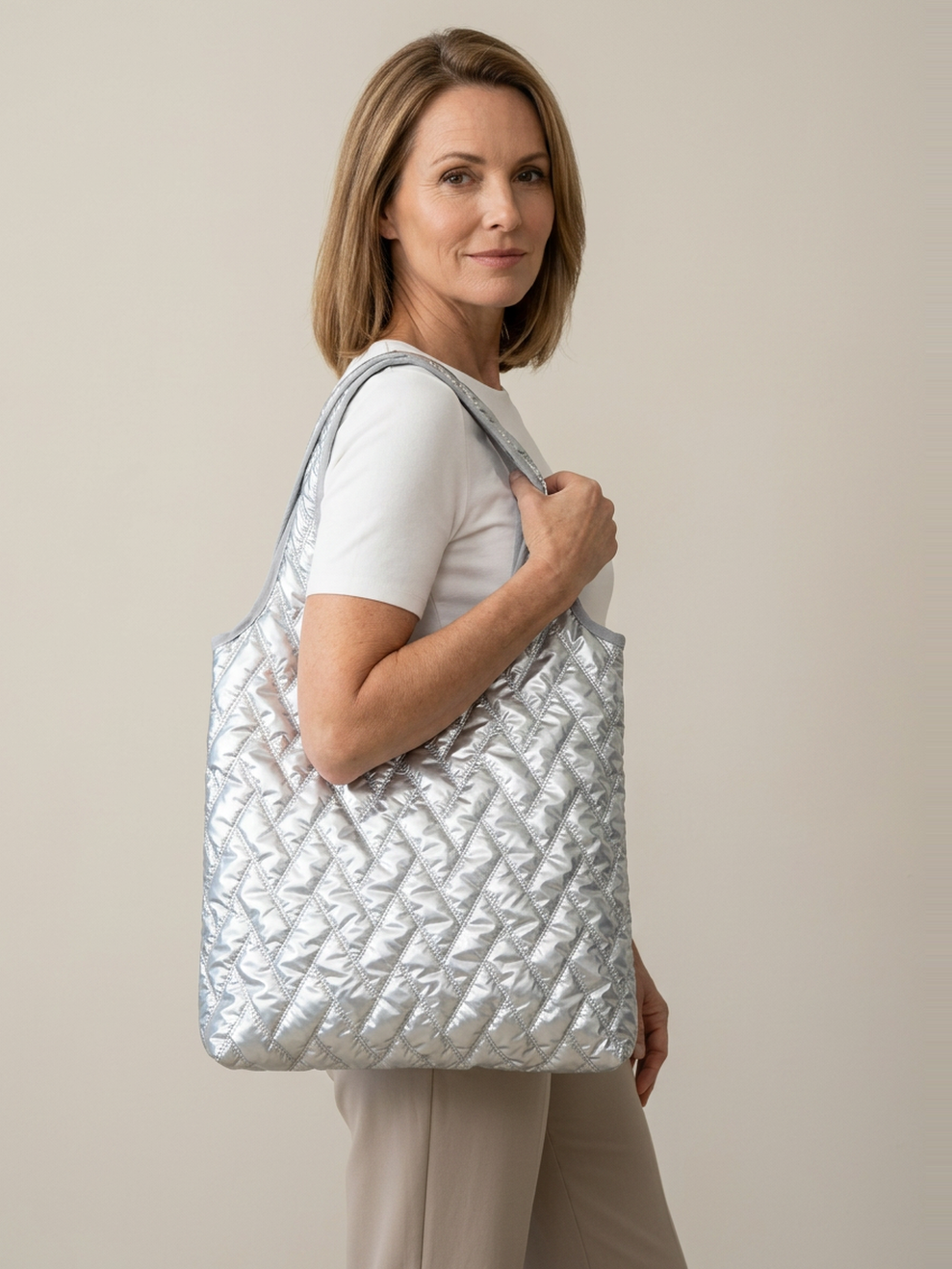 Mila Puffer Tote Bag in Silver carried by a confident woman in a clean studio setting.